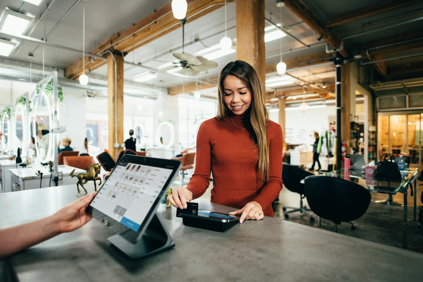 A smiling salon owner taking a card payment at the counter
